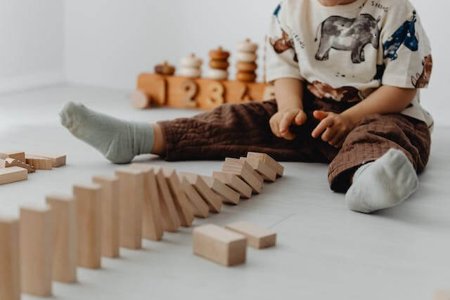 child knocking over row of blocks